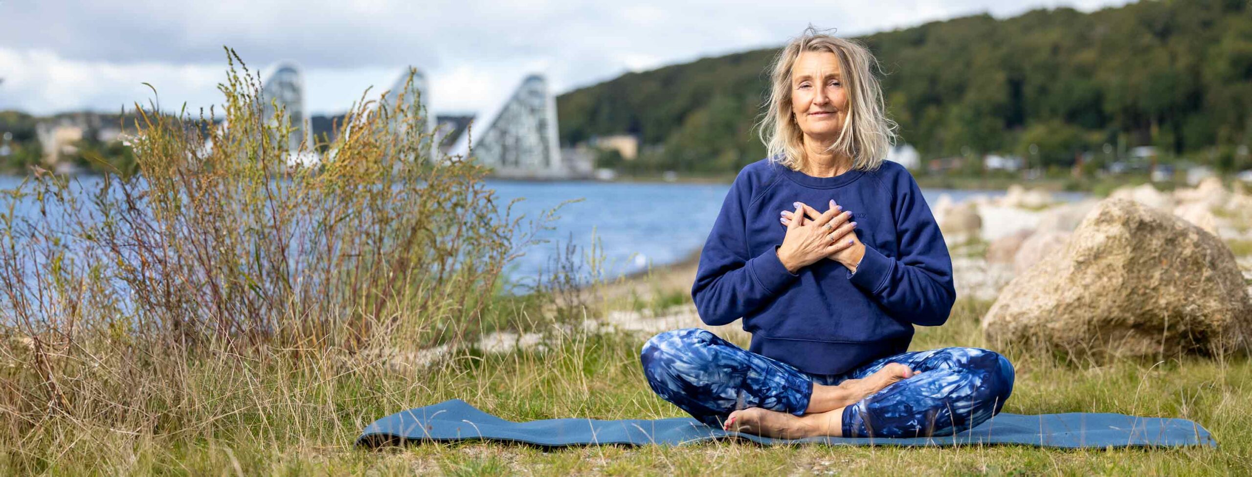 Dorthe Broeng sidder i meditation ved fjorden