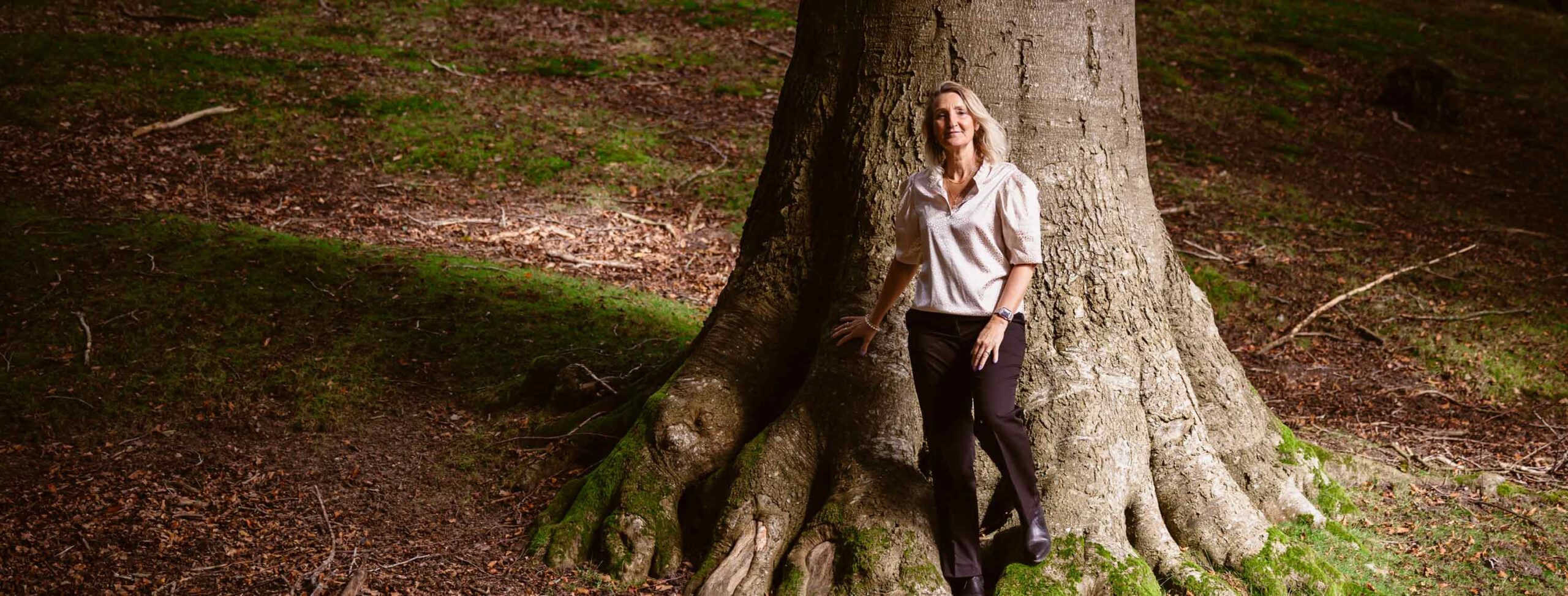 Dorthe Broeng står ved et stort træ i skoven