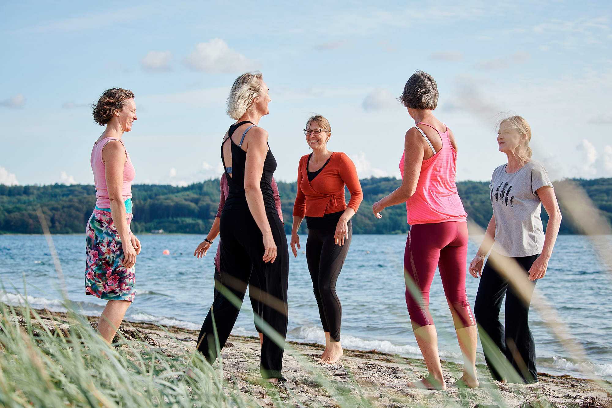 En gruppe kvinder laver shaking meditation på stranden