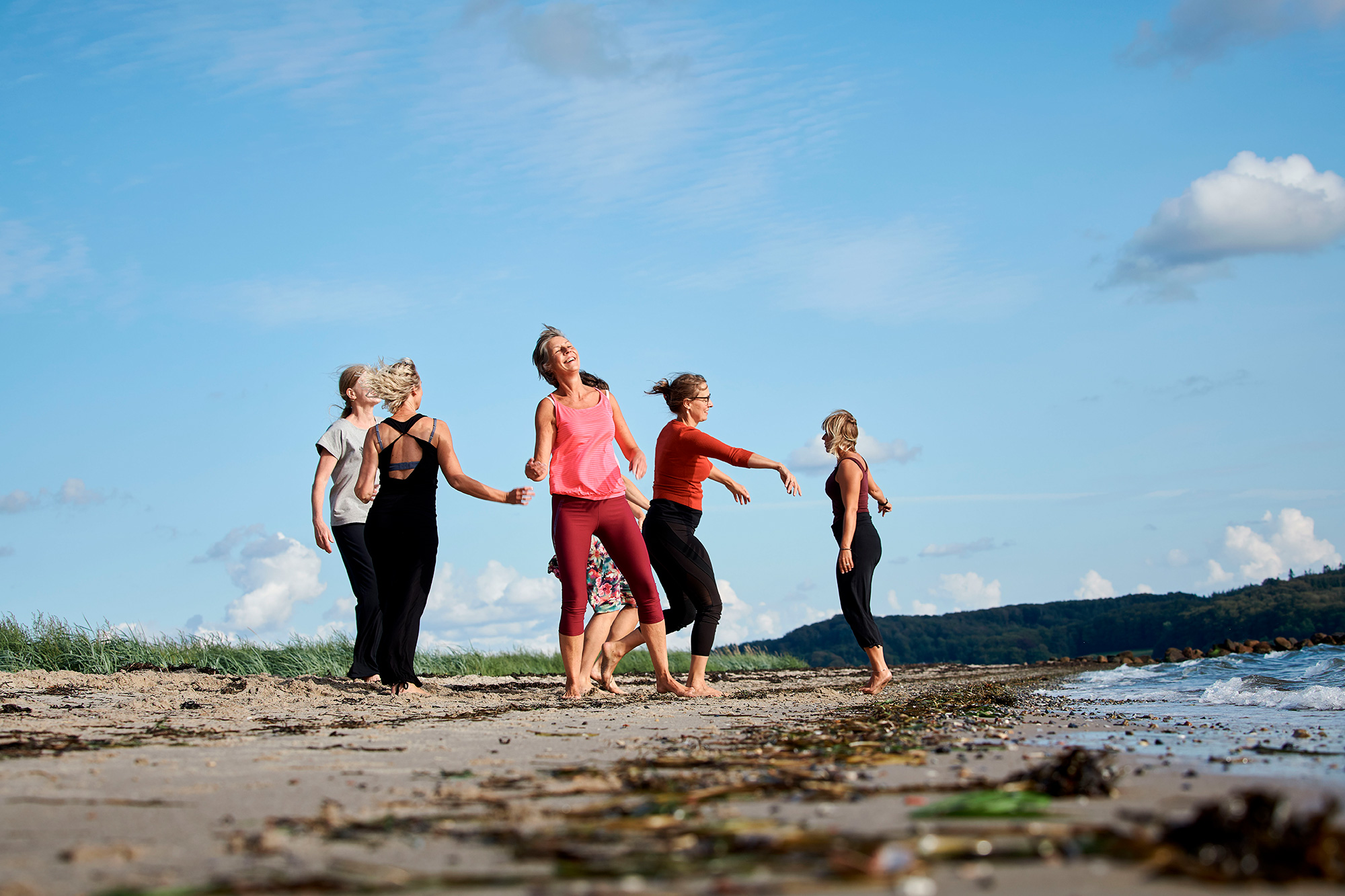 Kvinder bevæger sig frit på stranden under shaking meditation